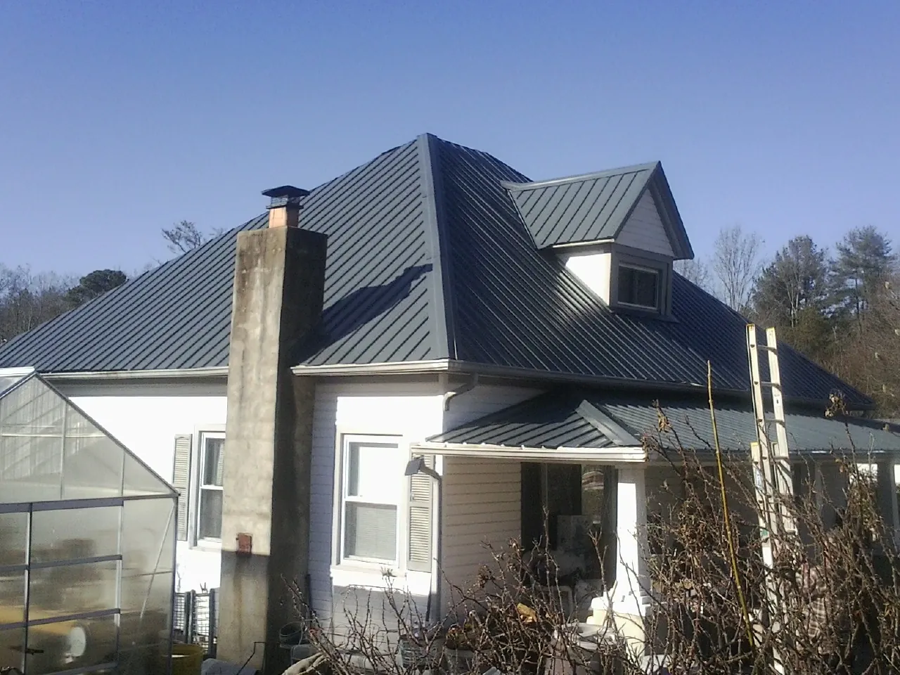 Dark blue standing seam metal roof on a white farmhouse with dormer — Slate & Tile Roof Repair by Roofing Brothers in Speed