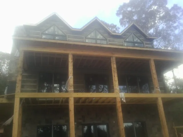 Dormers and porch framing on a large log home under construction — Roof Coating work by our crew in Speed