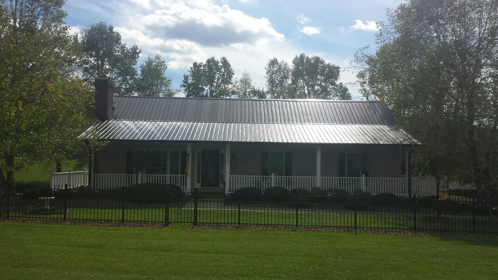 Gray metal roof on a brick ranch with a full width front porch — Gutter Guard Installation work by our crew in Speed