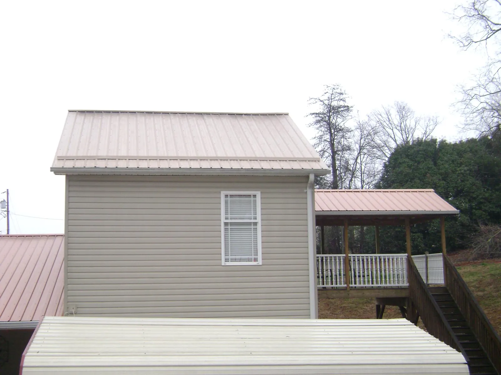Tan metal roofs on a two story addition and attached porch, from a Roof Replacement job in Speed