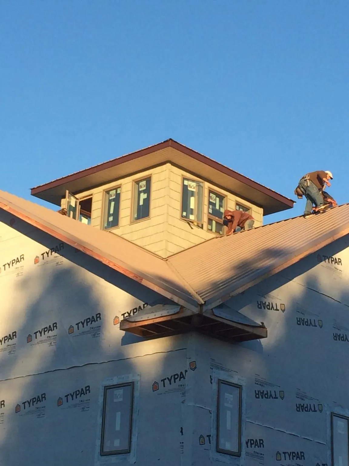 Roofers working around a rooftop cupola on a new metal roof at sunset — Roof Waterproofing in Speed by Roofing Brothers